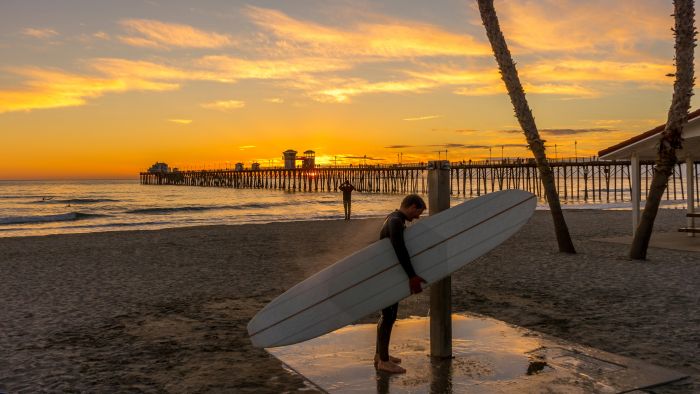 Surfer rinsing off at beach shower